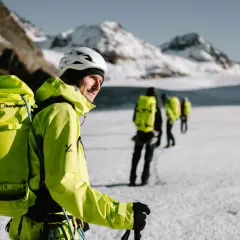 Bergsteiger mit leuchtend gelber Ausrüstung und Rucksäcken auf einer Gletscherwanderung. Die Packliste für die Hochtour ist komplett.