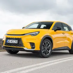 Żółty, kompaktowy SUV, który może być najmniejszym Lexusem, stoi na drodze.