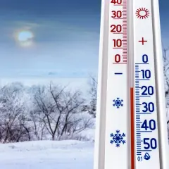 Termometr pokazuje -10°C, co zapowiada mroźną pogodę na styczeń 2026. Zimowy krajobraz z ośnieżonymi drzewami i bladym słońcem.
