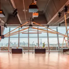 Salle de réception moderne avec vue panoramique sur Paris, éclairage néon, bar et scène. La Tour Eiffel est visible au loin.
