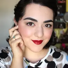 Mujer con un look de maquillaje años 40, labios rojos intensos, delineado de ojos y rubor rosado.
