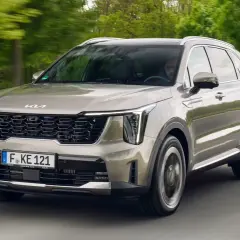 Un Kia Sorento preparado para la aventura, con su diseño moderno y elegante, avanza por una carretera rodeada de vegetación.