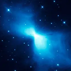 En lysande blå nebulosa, likt en fjäril, lyser upp den mörka rymden. Stjärnor glittrar runt den, en påminnelse om den extrema temperatur rymden kan ha.
