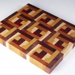 A beautiful diy cutting board with an intricate geometric pattern made from various wood types and red accents.