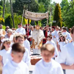 Procesja Bożego Ciała z monstrancją, księdzem i dziećmi w białych strojach.