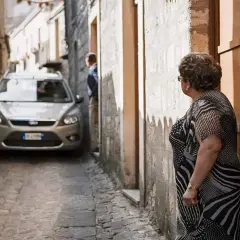 Navigating narrow Italian streets: a silver car is parked in a tight alleyway. Tips for driving in Italy for the first time include being prepared for tight squeezes.