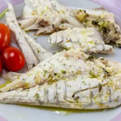 Delizioso branzino in padella, cotto alla perfezione e condito con erbe aromatiche. Servito con pomodorini freschi e rucola.