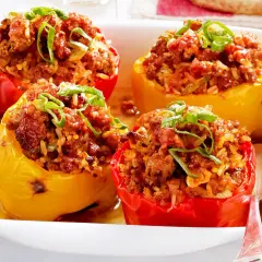 Gefüllte Paprika mit Hackfleisch und Reis, garniert mit Frühlingszwiebeln, in einer Auflaufform.
