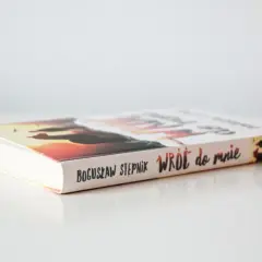 Książka Bogusława Stępnika "Wróć do mnie" na jasnym tle. Okładka z zachodem słońca i sylwetkami.