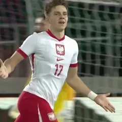 Młody piłkarz w białej koszulce z numerem 17 i godłem Polski cieszy się z bramki.