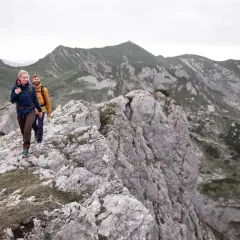 Zwei Wanderer genießen eine 5-tägige Tour durch die Alpen. Sie gehen auf einem felsigen Grat mit beeindruckender Bergkulisse.