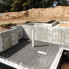 Bau einer Kellerbodenplatte mit Betonwänden und Bewehrung.