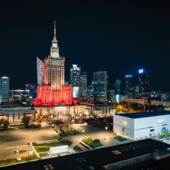 Warszawski Pałac Kultury i Nauki rozświetlony na czerwono, niczym scena przed wielkim koncertem. W tle nocna panorama miasta.