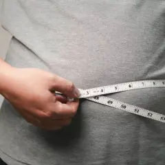 Person misst den Bauchumfang. Viele fragen sich, wo nimmt man zuerst ab – oft ist es der Bauch.