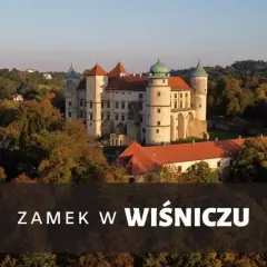 Majestatyczny zamek Wiśnicz otoczony jesiennymi drzewami, z charakterystycznymi wieżami i czerwonymi dachami.