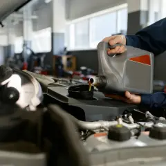 Mechanik wylewa olej do silnika. Zastanawiasz się, ile kosztuje wymiana oleju w silniku?