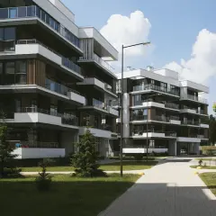 Nowoczesne bloki mieszkalne z balkonami i zielenią wokół.