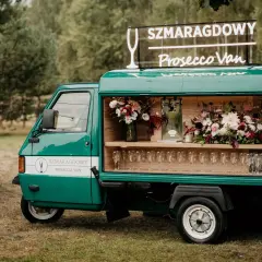 Zielony Prosecco Van "Szmaragdowy" z neonem i kwiatami, gotowy na przyjęcie.
