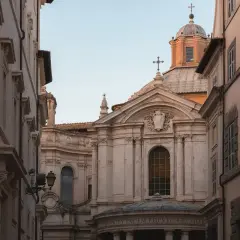 La facciata barocca della chiesa di Santa Maria della Pace si staglia tra palazzi romani, con la sua cupola imponente e le decorazioni scultoree.