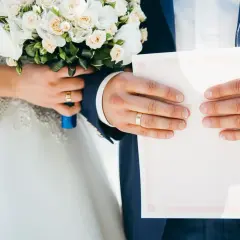 Para młoda trzyma bukiet i dokument. Zastanawiasz się, ile się daje na wesele?