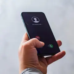 Dłoń trzyma smartfon z ekranem pokazującym przychodzące połączenie. Zastanawiasz się, jak zadzwonić z numeru prywatnego?