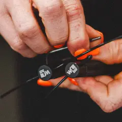 Hände mit orangen Nägeln stellen ein Springseil ein. Die Frage "wie lang muss ein springseil sein" wird hier visuell beantwortet.