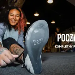 Uśmiechnięta kobieta zakłada buty do wspinaczki na ściance. Dowiedz się, bouldering co to jest i jak zacząć.
