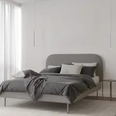 Minimalistyczna sypialnia z łóżkiem i dwoma lampami wiszącymi tuba, które dodają nowoczesnego charakteru.