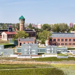 Widok na teren pokopalniany z wieżą wyciągową, wieżą ciśnień i nowoczesnymi szklanymi budynkami.