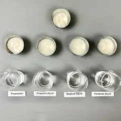 Sześć próbek kremów w małych pojemnikach i cztery zlewki z płynami: propanediol, glikol propylenowy, **butylene glycol** i pentylene glycol.