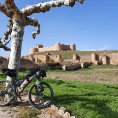 Bicicleta de montaña lista para rutas en bici por Soria, con un castillo medieval al fondo.