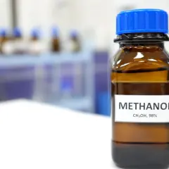 Brązowa butelka z niebieską zakrętką zawiera metanol, 98%. Substancja ta ma szerokie zastosowanie w przemyśle chemicznym.