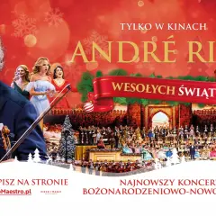 André Rieu w smokingu z skrzypcami, na tle orkiestry i chóru w świątecznej scenografii.