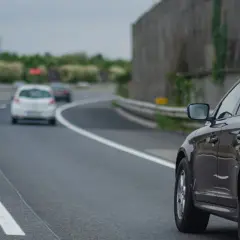 Czarny SUV na autostradzie, obok białe samochody. Pamiętaj, kiedy można wyprzedzać z prawej strony, by uniknąć korków.
