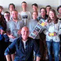 Gruppe von Schülern und einem Mann, der ein Buch von Dietmar Schultke hält.