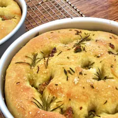 Focaccia senza glutine dorata, con rosmarino e sale grosso, appena sfornata e pronta per essere gustata.
