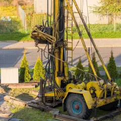 Żółta wiertnica na podwórku, gotowa do pracy. Zastanawiasz się nad studnia głębinowa koszt?
