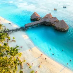 Rajska plaża z palmami i turkusową wodą. Restauracja na wodzie, ludzie odpoczywają. Zanzibar czy warto? Zdecydowanie tak!