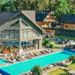 Hotel Bacówka Radawa: basen, leżaki i drewniane domki w otoczeniu lasu.