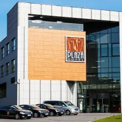 Warsaw Plaza Hotel z nowoczesną fasadą i zaparkowanymi samochodami.