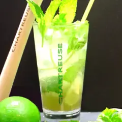 Un verre de cocktail Chartreuse, garni de menthe fraîche et de citron vert, prêt à être dégusté.