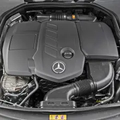 Silnik Mercedes-Benz E-Class. Widoczny czarny plastikowy dyfuzor, logo gwiazdy Mercedesa i elementy układu dolotowego.