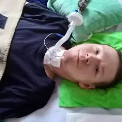 Chłopiec z dystrofią mięśniową Duchenne'a leży w łóżku, podłączony do respiratora.