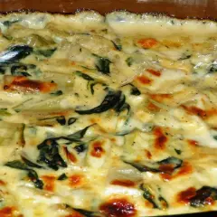 Un gratin crémeux de côte de blette, doré au four, avec des touches de vert et des bords légèrement caramélisés. Un délice réconfortant.