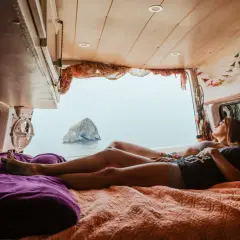 Deux amies profitent d'une vue imprenable sur la mer depuis leur spot van en Normandie.