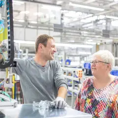 Zwei Kollegen in einer Fabrikhalle, die über ihre Arbeit sprechen. Vielleicht diskutieren sie, wie wird man Betriebsrat, um die Arbeitsbedingungen zu verbessern.