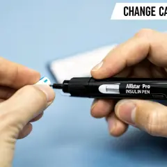 Instrukcja jak wymienić insulinę w penie. Dłoń trzyma czarny pen z napisem "Allstar Pro INSULIN PEN" i wyjmuje z niego białą końcówkę.