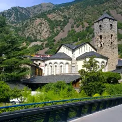 La parroquia de Escaldes-Engordany, con su torre románica, se alza majestuosa entre montañas verdes y edificios tradicionales.
