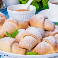 Pyszne, kruche rogaliki posypane cukrem pudrem, udekorowane listkami mięty. Idealne na deser lub do kawy.