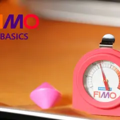 Termómetro FIMO para hornear arcilla. Un trozo de arcilla rosa y un termómetro rojo con la marca FIMO.